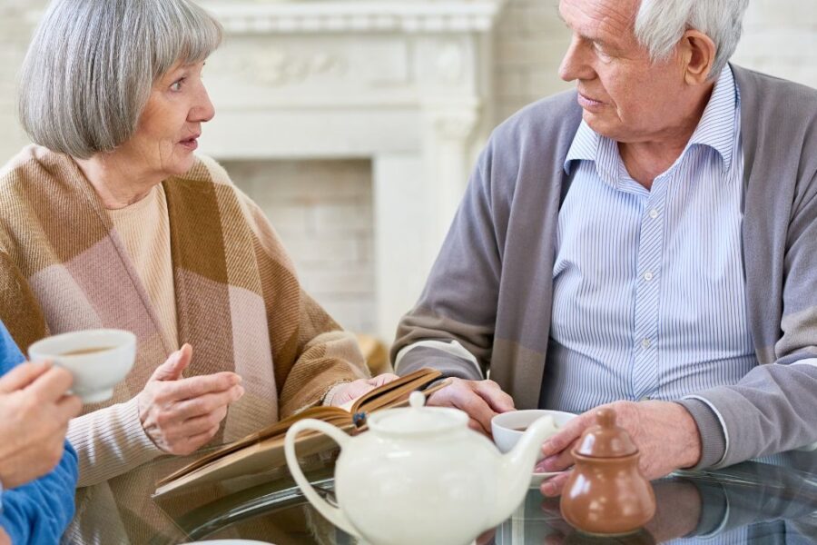 an older couple having tea in winter with warm drinks