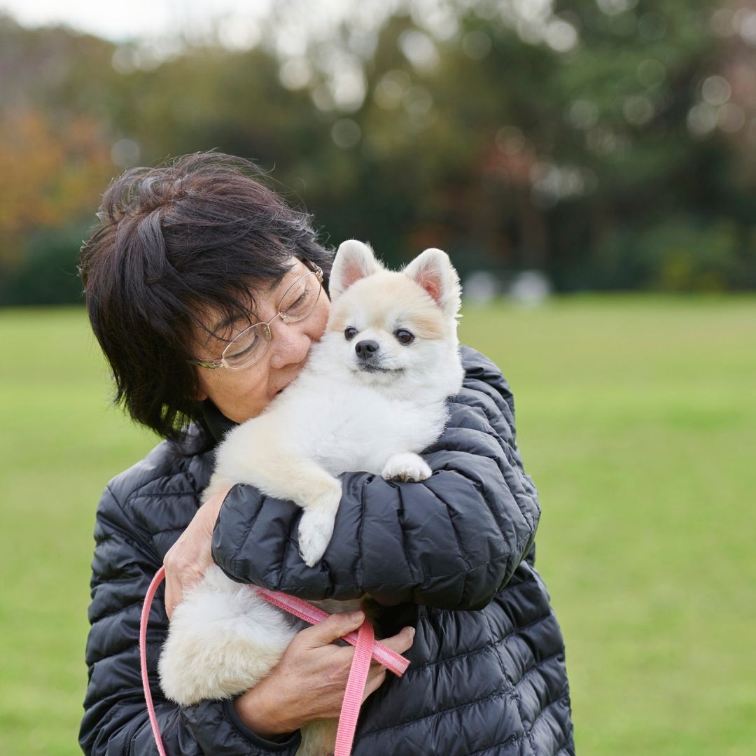woman hugging small white dog
