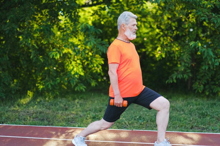 Senior man doing lunges outdoors.